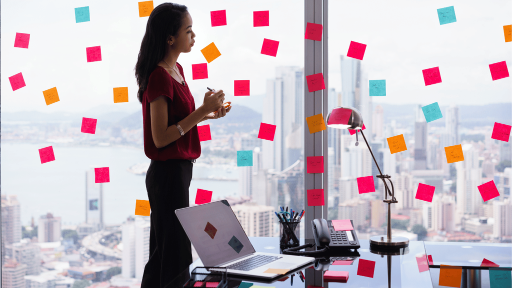 Woman with post it notes on window and desk with unfinished tasks and to do list