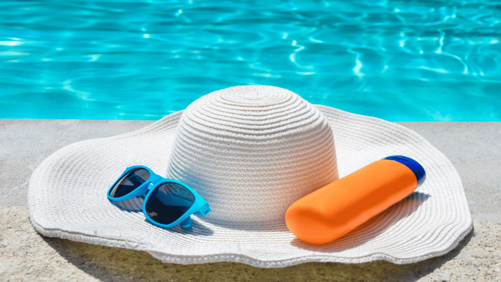 Sun hat on beach with sunscreen and sunglasses